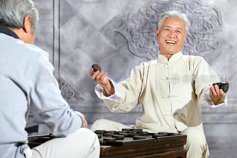 two oriental senior adults play chinese chess